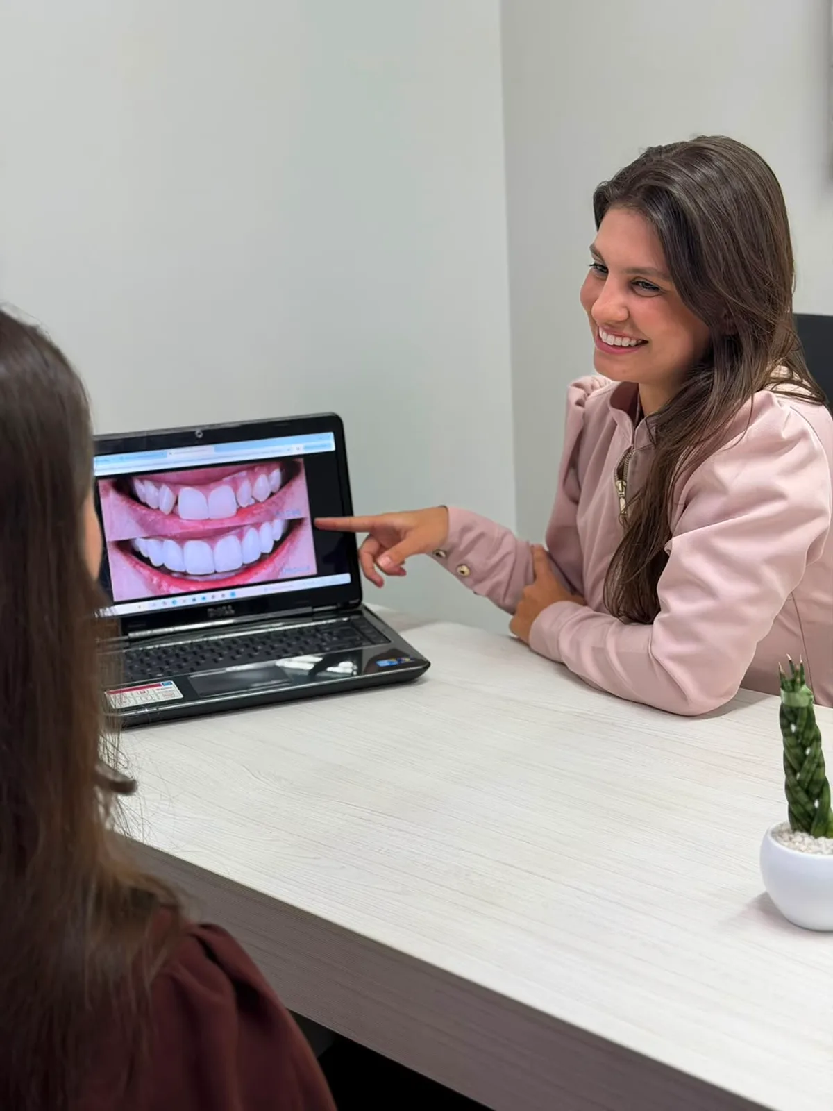 Dra. Thais Weber sorrindo ao apresentar o planejamento do sorriso a uma paciente